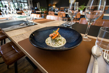 Une soupe aux crevettes dans une assiette posée sur une table dans un restaurant gastronomique