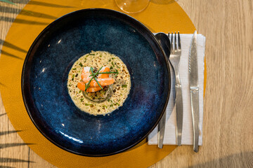 Une soupe aux crevettes dans une assiette posée sur une table dans un restaurant gastronomique