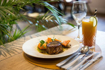 Une viande et des patates dans une assiette dans un restaurant gastronomique