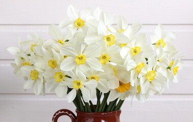 Bouquet of white and yellow daffodils in a brown vase as floral background