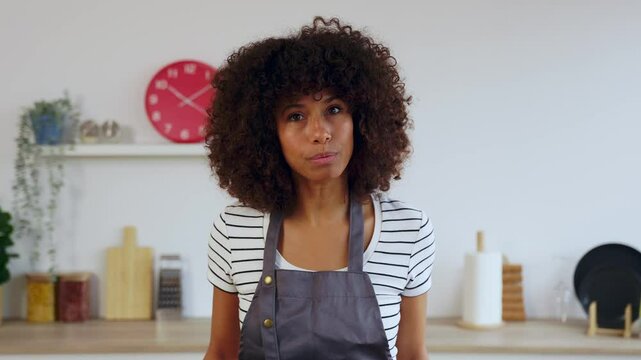 POV of happy chef woman wearing apron explaining recipe while talking to the camera recording cooking show video in kitchen at home. E-learning, side hustle and vlogger people concept