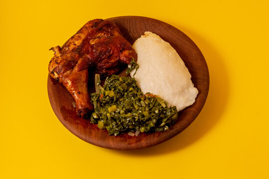 Crisped grilled quarter chicken, accompanied by traditional African food (ugali) and stir-fried kale	