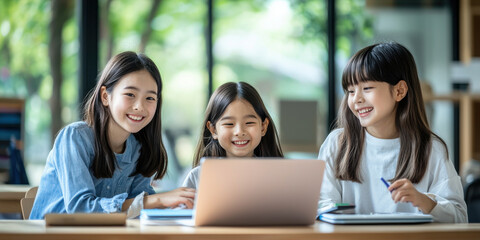 Engaged girls learning together on laptop in bright classroom