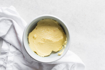 Overhead view of organic butter in a white plate with handle, natural butter from grass fed cows