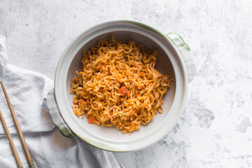 Overhead view of Spicy instant noodles with minced pork in a claypot, top view of spicy ramen noodles with pork in a donabe