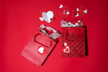Two red gift bags with white hearts on a red background