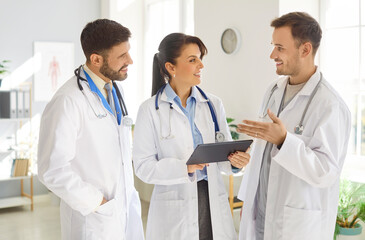 Professional team of doctors and nurses cooperates during a work meeting in a hospital office, using a tablet PC for research and teamwork, highlighting collaboration in healthcare.