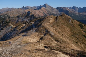 Scenery of autumn Tatras Mountains with single silhouette of hiking person. Czerwone Wierchy range from around Kasprowy Wierch Peak, Tatras Mountains, Poland.  