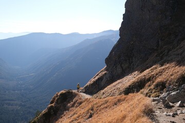 Scenery of autumn Tatras Mountains with very little silhouette of hiking person on trail. Czerwone Wierchy range from around Kasprowy Wierch Peak, Tatras Mountains, Poland.  