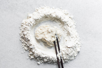 Overhead view of hot water dough being mixed on granite countertop, top view of scallion pancake dough being mixed, process of making scallion pancakes or cong you bing