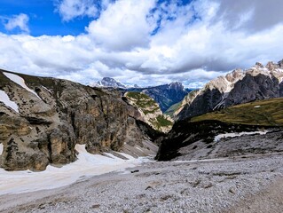 Fototapeta premium Panoramic alpine valley with snow-covered slopes and limestone peaks in the Dolomites, Italy