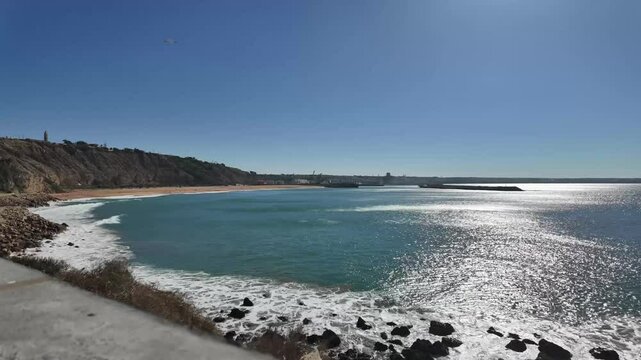 motion lapse video captures the scenic coastal view from "Ras Lafaa" in Safi, Morocco, showcasing the expansive ocean, clear sky, and lush greenery in the foreground