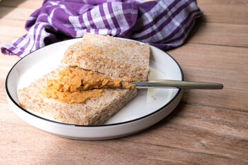Peanut butter being spread on whole wheat bread. A simple and classic snack or breakfast