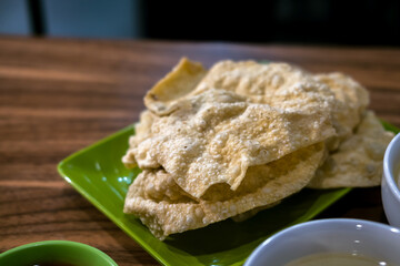 Selective focus , Crispy, golden fried wonton crackers on a green plate. A popular Indonesian snack, often served with noodles or as an appetizer.