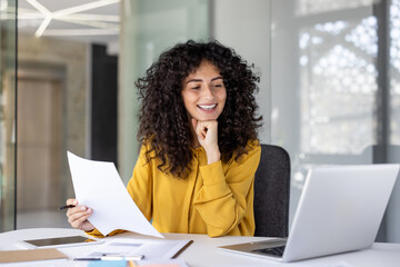 Satisfied businesswoman smiling holding report in hands, office worker among papers and contracts...