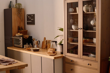 Tall wooden cupboard full of ceramic polished tableware next to wooden minimalist base cabinets...