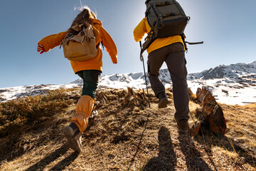 Couple of young active hikers are climbing uphill in mountains