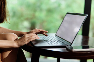 A young woman typing on a laptop in a cozy workspace, expressing focus and creativity, surrounded by a serene green background