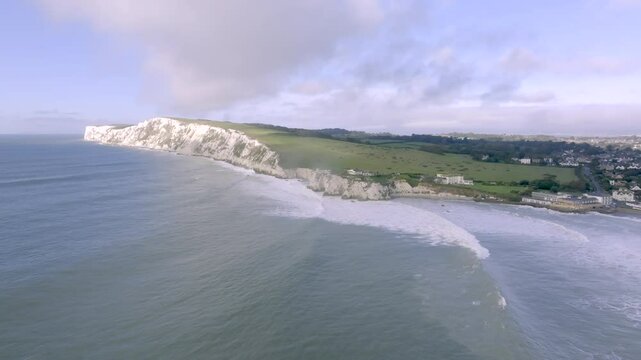 A beautiful ocean view with a white cliff in the background. The sky is clear and the water is calm