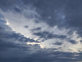 Obraz premium Dramatic dark blue clouds with sun shining behind it, Natural background texture 