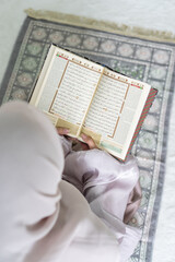 moslem islam woman female girl read Quran holy book prayer mat vertical overhead view