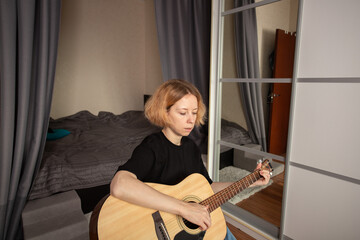 Guitar lessons at home, practicing chords on an acoustic guitar, woman studying music as a hobby.