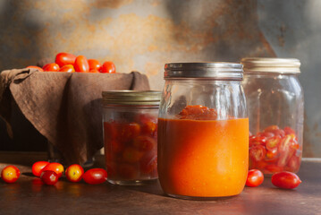 homemade tomatoes sauce in a glass bottle jar on brown rustic table.