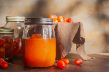 homemade tomatoes sauce in a glass bottle jar on brown rustic table.
