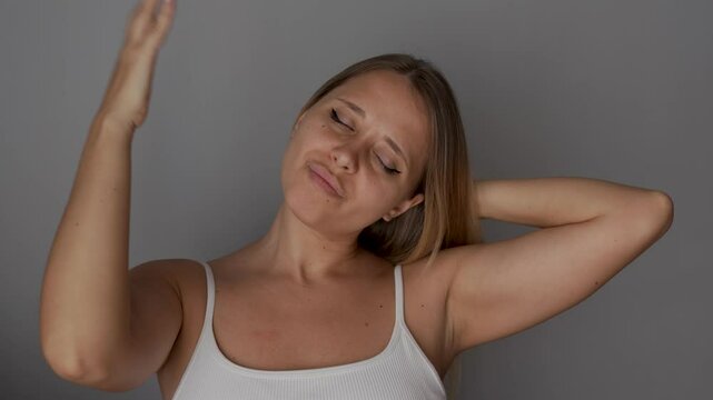 Young caucasian blonde woman waving her hand at herself because of the heat on a dark grey background. Sweating due to hormonal imbalance, hot air temperature