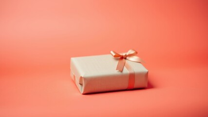 A simple gift box wrapped in brown paper with a delicate peach ribbon bow on a vibrant coral background.