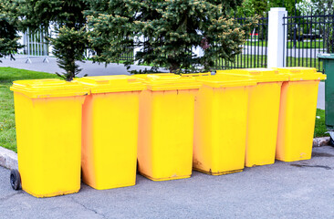 A row of new yellow waste containers at the city street. Modern garbage bins