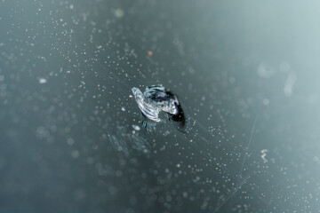 Close-up view of a chipped windshield from stone impact on a vehicle during daytime