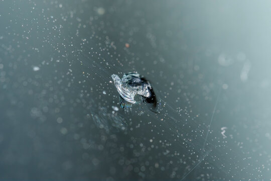 Close-up view of a chipped windshield from stone impact on a vehicle during daytime