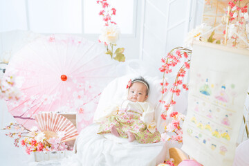 初節句のひな祭りで春の桜に囲まれて嬉しそうな赤い袴姿の可愛い女の子赤ちゃん