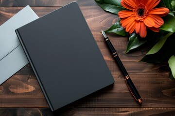 A black notebook sits on a wooden table with a pen and a flower