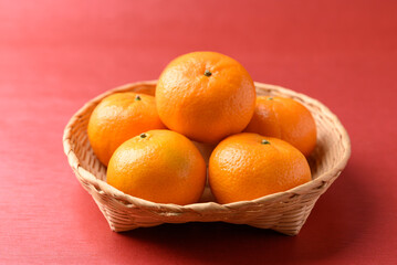 Mandarin tangerine orange fruit in basket on red background, Lucky food in Lunar New Year or Chinese New Year