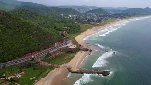 Aerial drone shot of Vizag city during dusk, with the city lights illuminating the streets and the ocean in the distance.