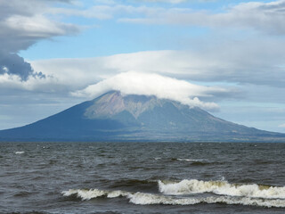 Majestic volcano with cloud cover viewed from tranquil lakeshore on clear day