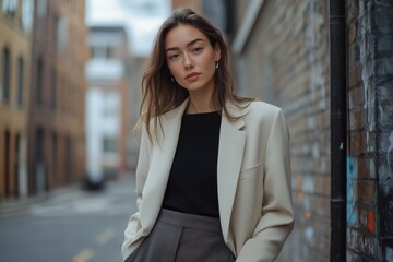 Elegant woman in streetwear, cream blazer and grey trousers emphasizing the scene
