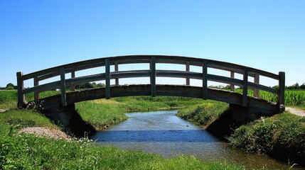 Obraz premium A rustic wooden bridge crossing a stream under the radiance of a clear blue sky.
