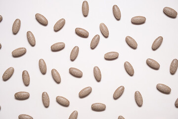 Vitamin pills are scattered on beige background.
