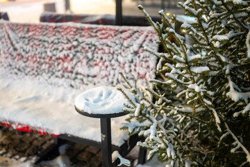 a resting place, snow on a bench and fir trees