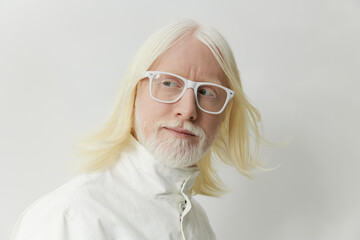 Stylish older man with long white hair and glasses against a minimalistic white background, exuding...