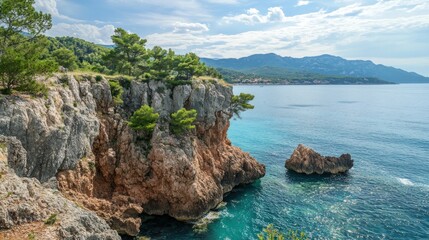 Fototapeta premium Coastal Cliffs with Turquoise Sea and Distant Mountains Under a Bright Sky Scene