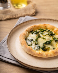 esfiha de escarola com mussarela em um prato sob uma mesa de madeira 