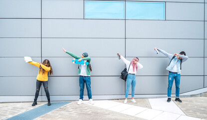 Happy multiracial teenage friends in casual clothes dancing dub dance on grey wall background after...