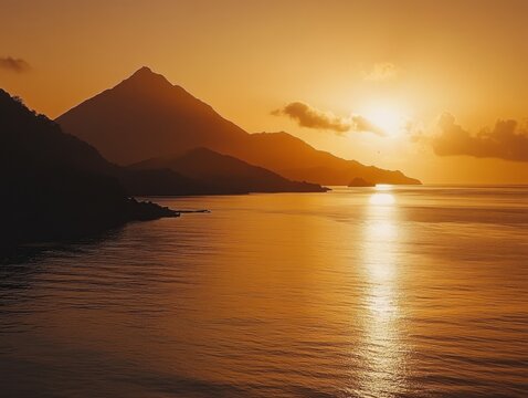 Golden sunset over calm sea with silhouetted mountains providing a dramatic view