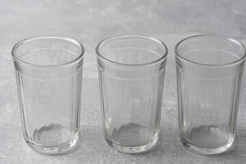 Three empty glasses on gray background. Copy space for text.