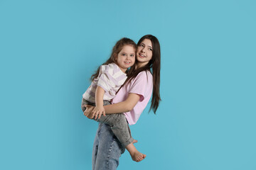 Portrait of cute sisters on light blue background