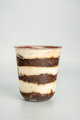 Tiramisu in a clear plastic cup showing the layers isolated on white background